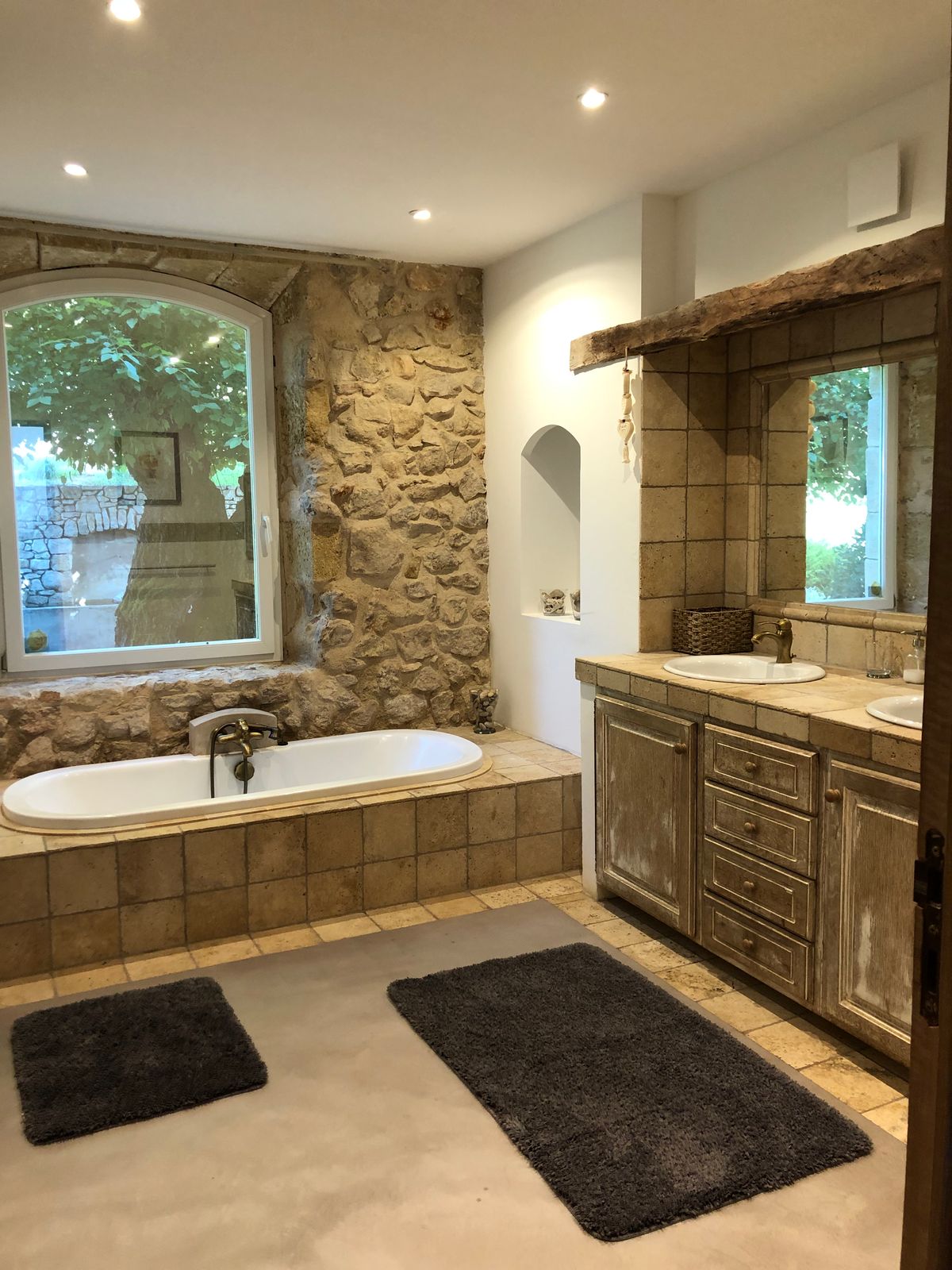 Room 2’s large bathroom: a bath beneath a window, stone wall and double basin.