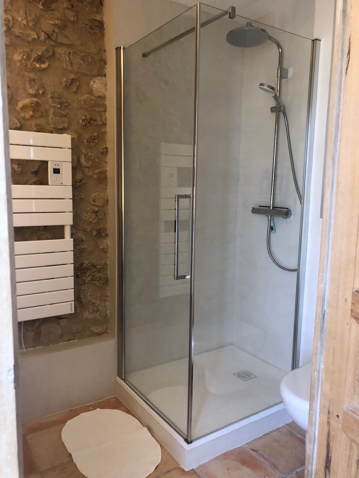 Room 3’s glass shower and heated towel rail, against the stone wall.