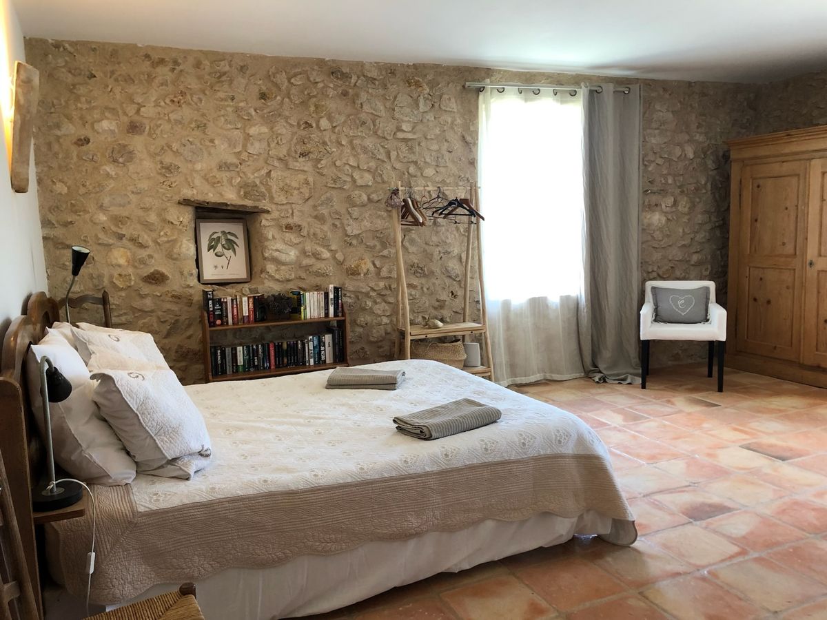 Room 3: double bed, stone wall, pine wardrobe, armchair and terracotta floor.