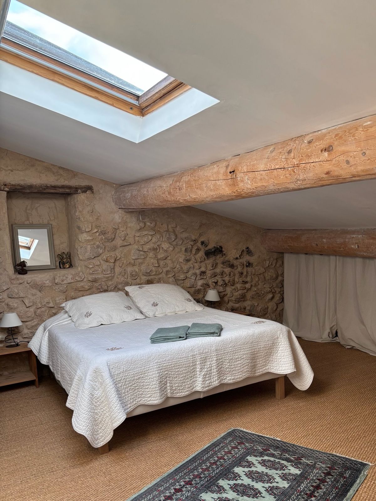 Room 6, upstairs: double bed under the beams, lit by a roof window.