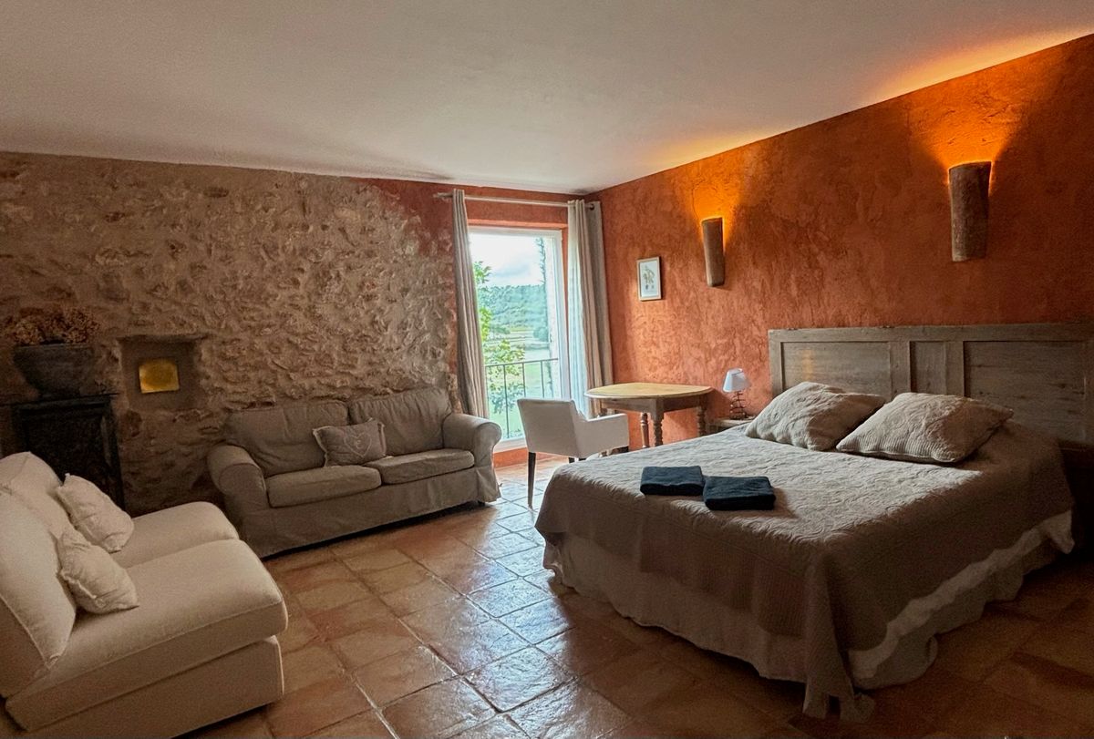 Room 2: ochre and stone walls, double bed, sofa, table and French window.