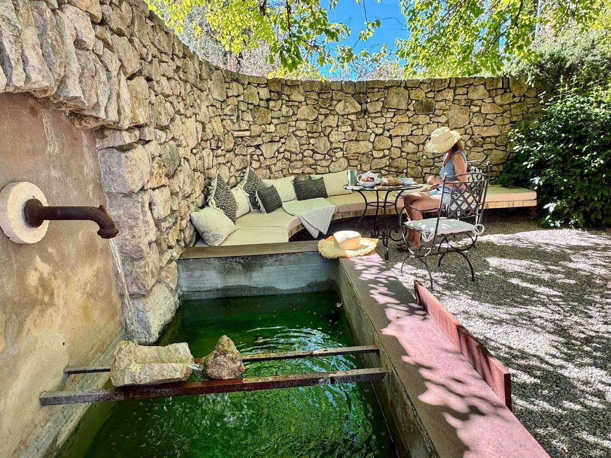 La fontaine de la cour et son bassin ; derrière, la banquette le long du mur, où l’on lit à l’ombre.