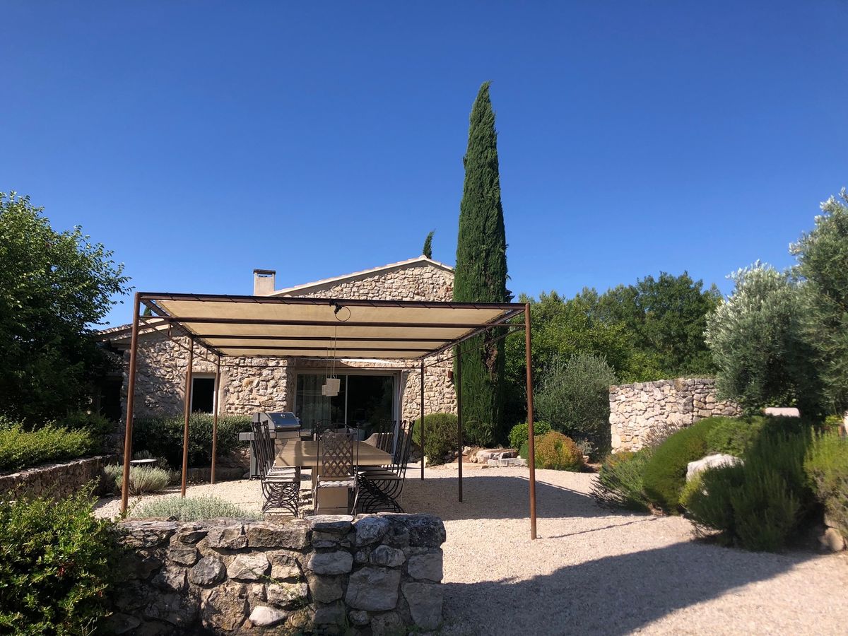 The south front of the house, the pergola and its table, a tall cypress and beds of lavender.