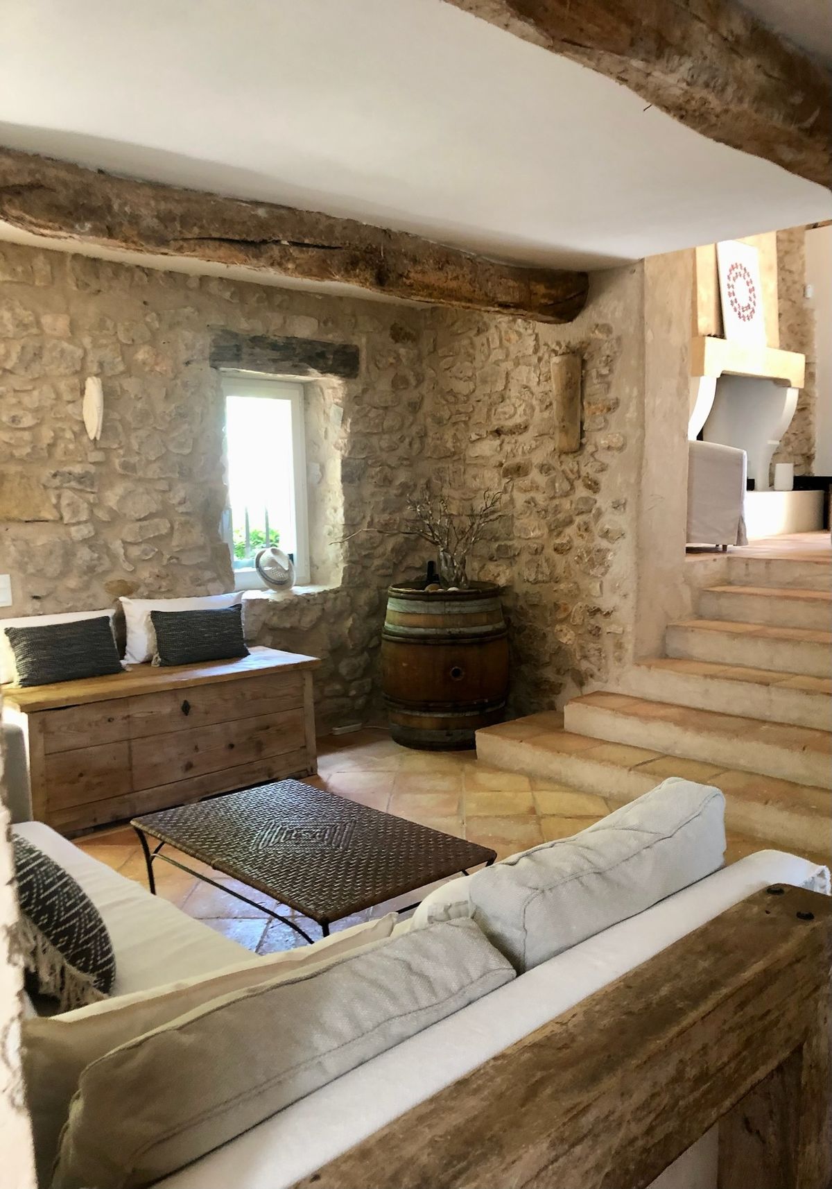 The living room: sofas, stone walls, beams and the few steps that separate the spaces.