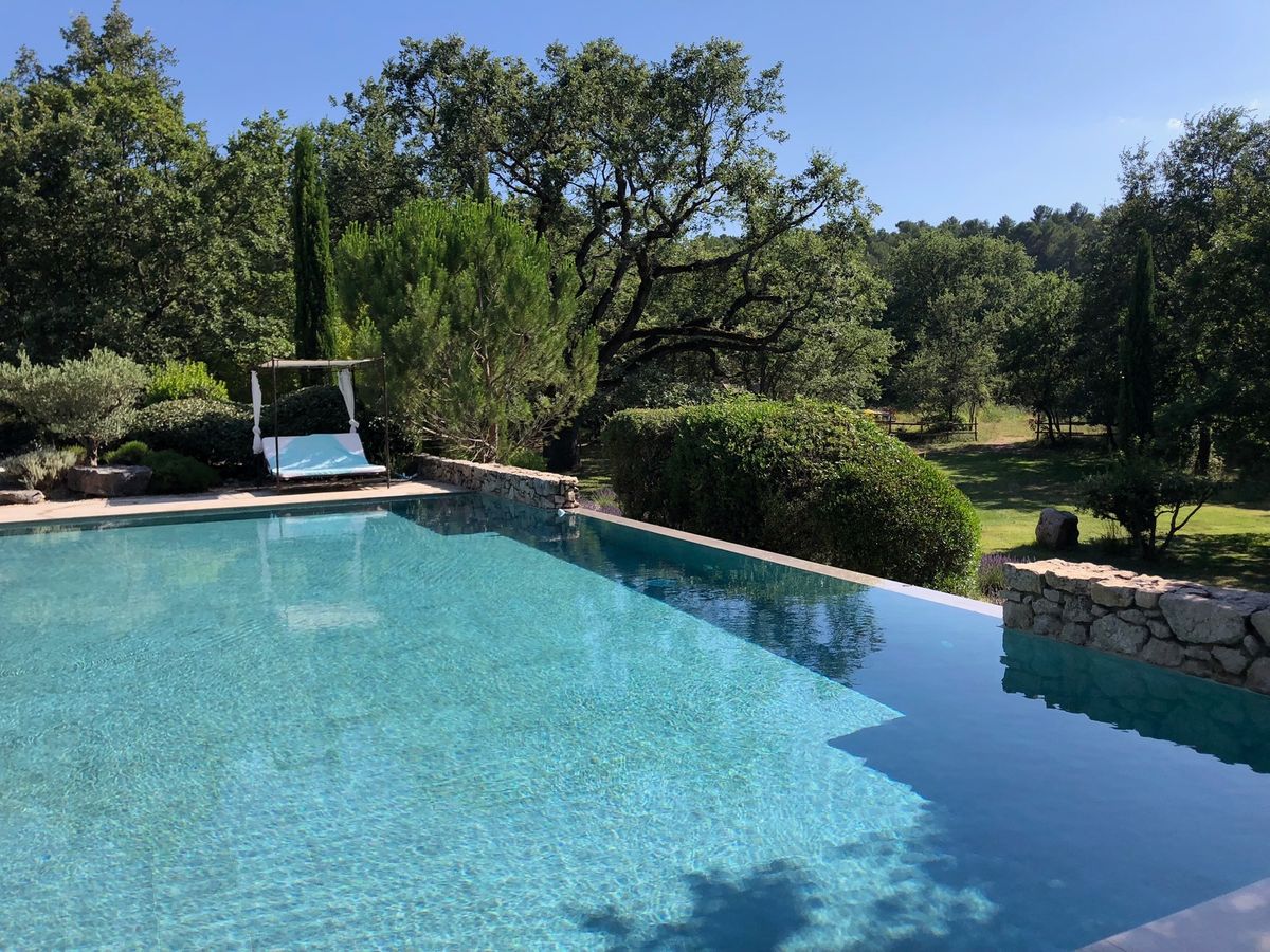 La piscine à débordement de 13 × 8 m, bordée de chênes, de cyprès et d’un lit d’extérieur ombragé.