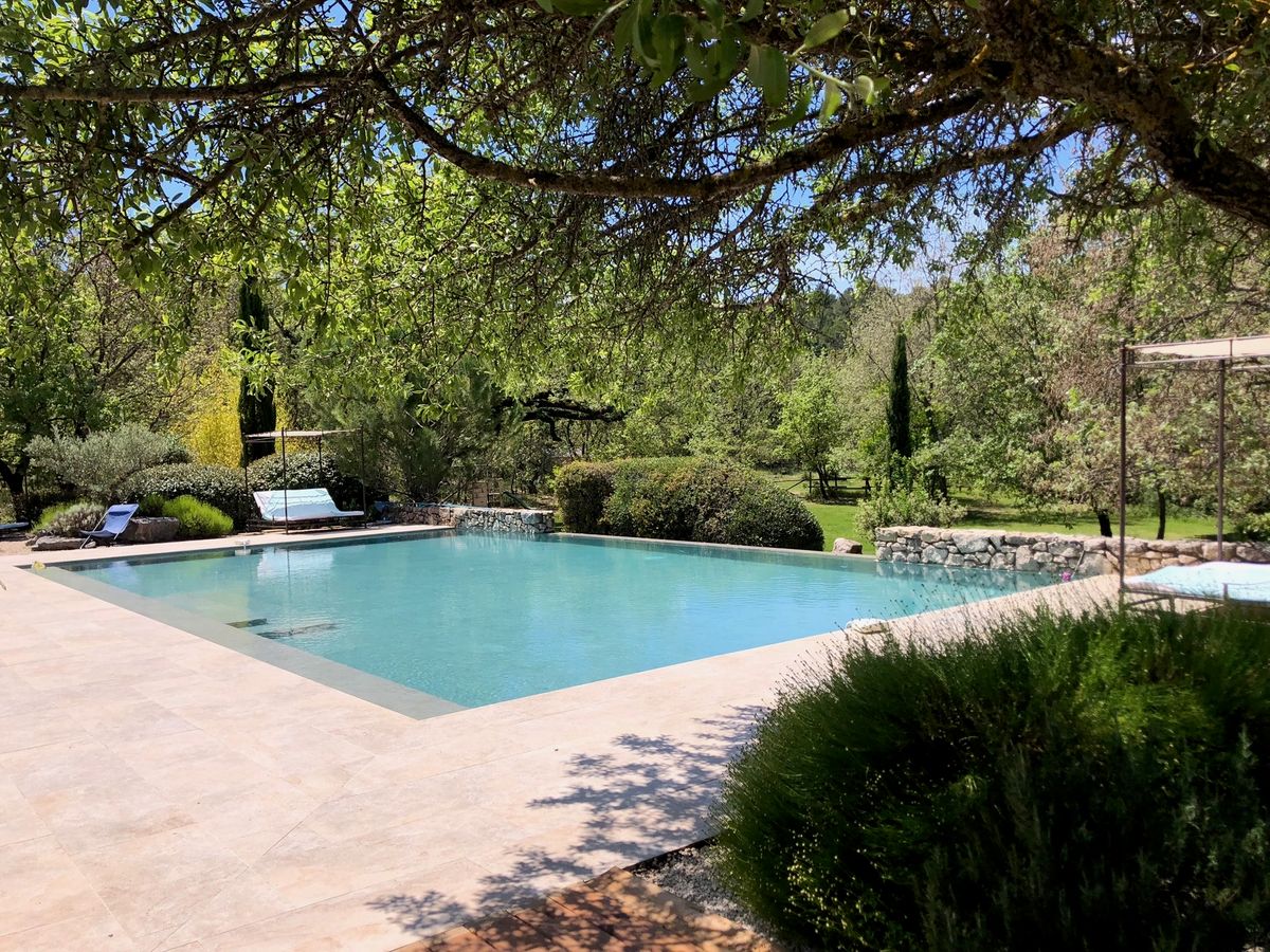 La plage de la piscine à l’ombre d’un chêne, face aux arbres du parc.