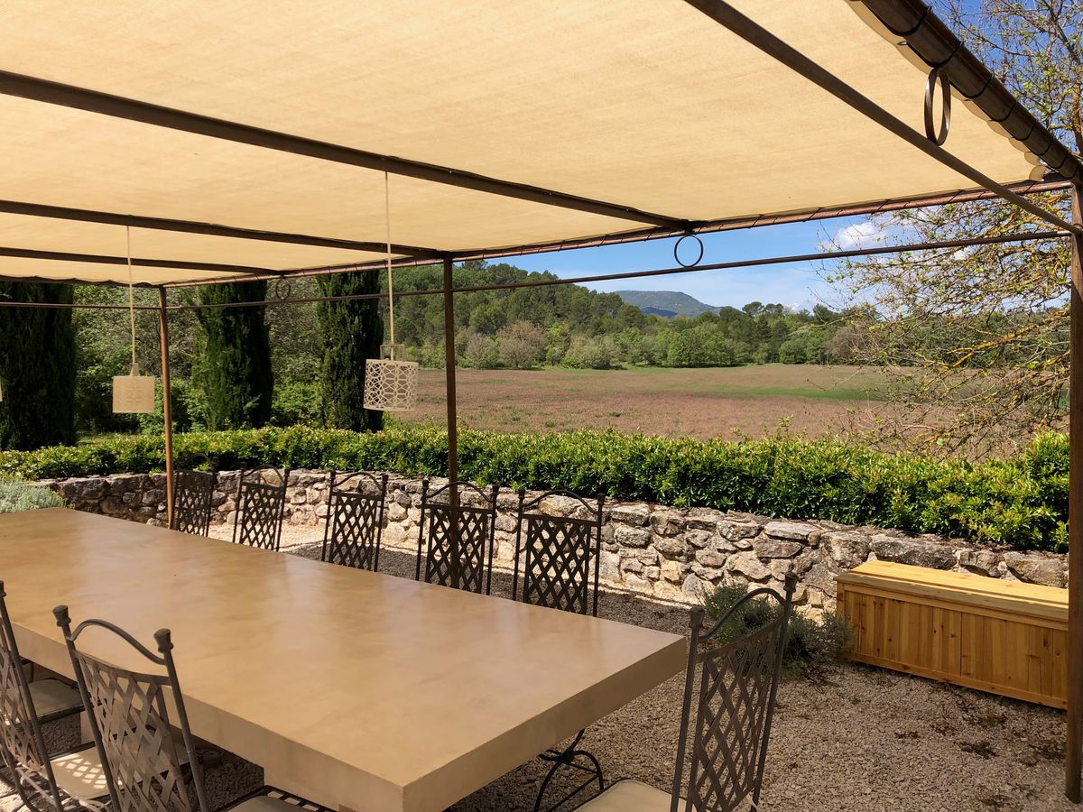 The pergola table and its wrought-iron chairs, facing the fields and hills.