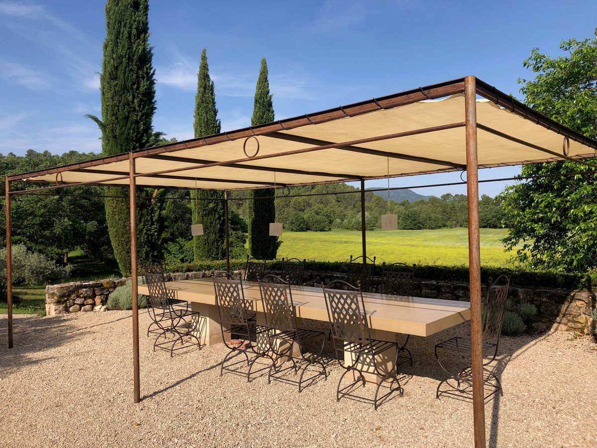 The south terrace: a long table for twelve under the pergola, looking out over the fields and cypresses.