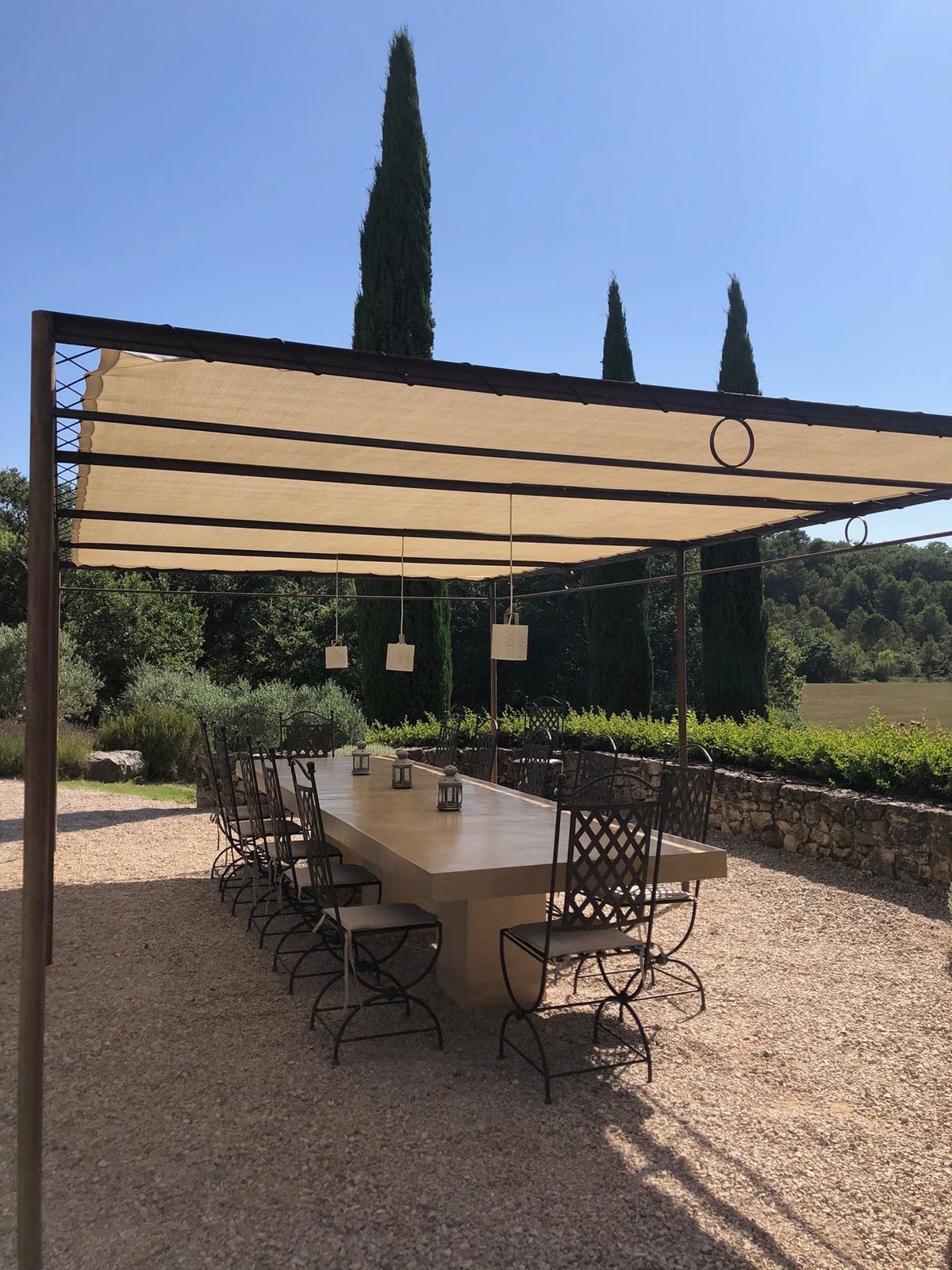 The pergola and its long table, with three cypresses behind.