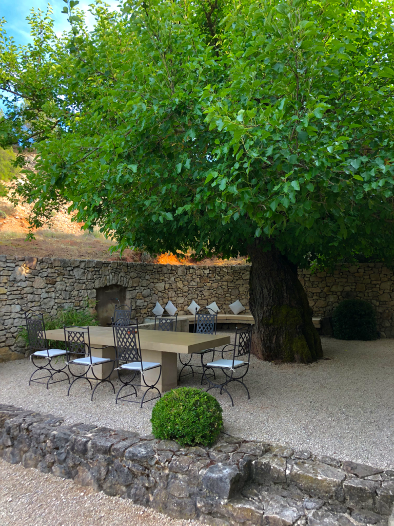 terrace with table and fountain in the shade of a century-old wall